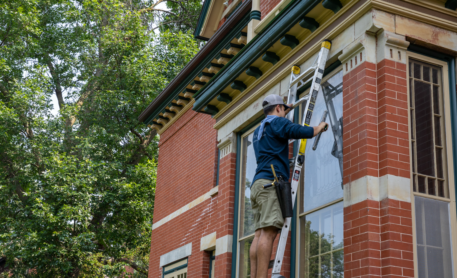 Klean Home Detailing technician cleaning upper-story windows
